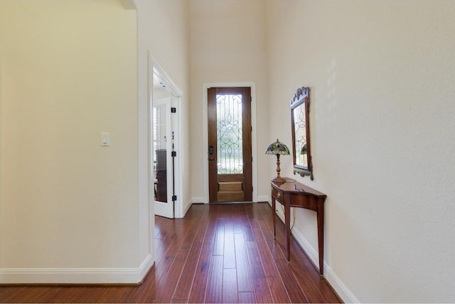 foyer featuring baseboards, dark wood-style floors, and a towering ceiling