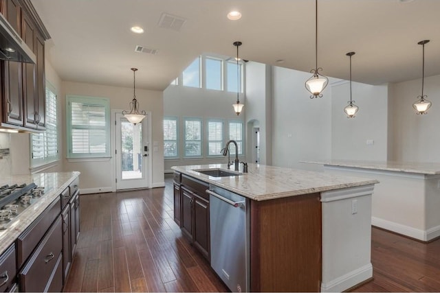 kitchen with visible vents, wall chimney range hood, a center island with sink, appliances with stainless steel finishes, and a sink