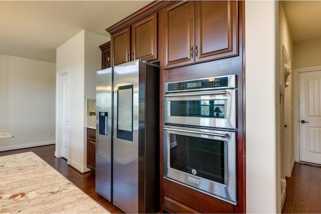 kitchen featuring baseboards, dark wood-style flooring, light stone countertops, and stainless steel appliances