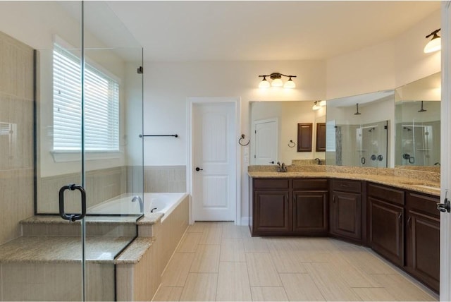 bathroom featuring double vanity, a garden tub, a stall shower, and a sink