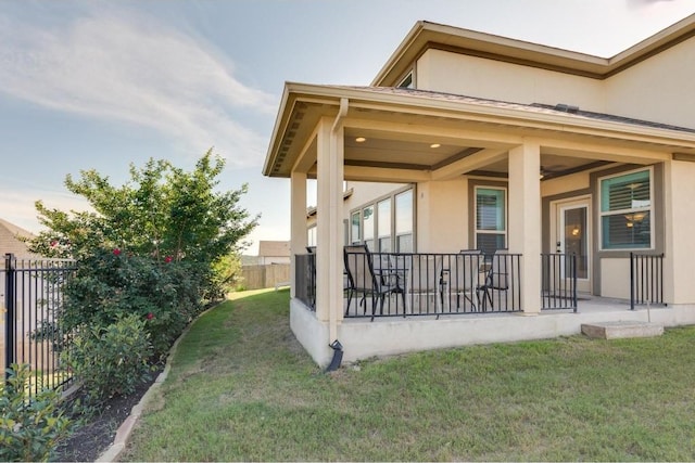 exterior space with stucco siding, a yard, and fence