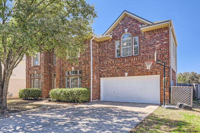 traditional-style home featuring brick siding, driveway, an attached garage, and fence