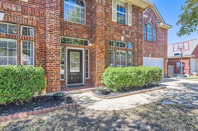 entrance to property with a garage and brick siding