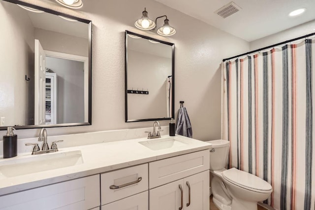 full bathroom with double vanity, toilet, visible vents, and a sink