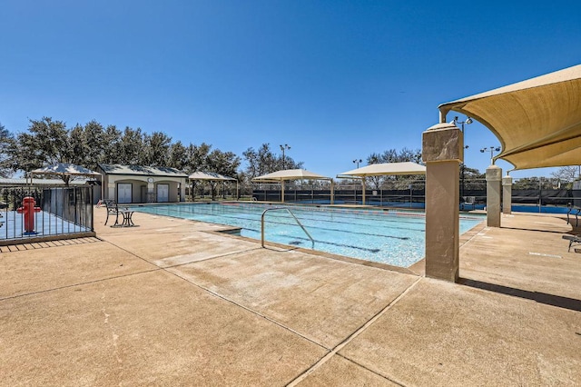 community pool with an outdoor structure, a patio, and fence