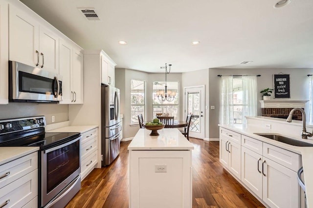 kitchen with visible vents, a sink, a kitchen island, white cabinetry, and appliances with stainless steel finishes