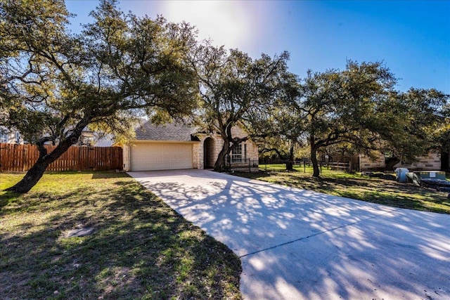 view of front of house with a front yard, concrete driveway, a garage, and fence