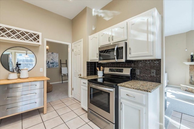 kitchen with tasteful backsplash, white cabinetry, appliances with stainless steel finishes, light tile patterned floors, and stone counters