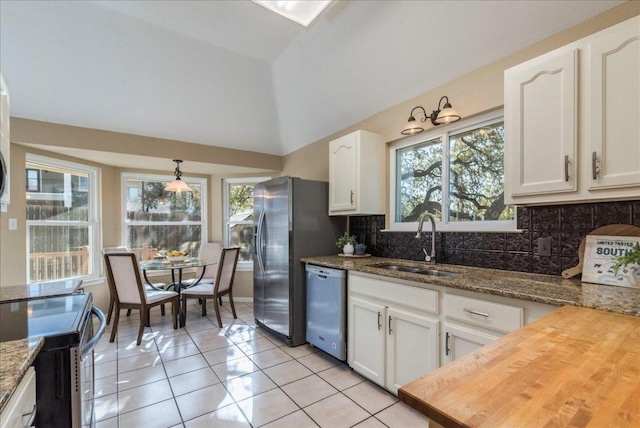 kitchen with a sink, vaulted ceiling, white cabinets, appliances with stainless steel finishes, and tasteful backsplash