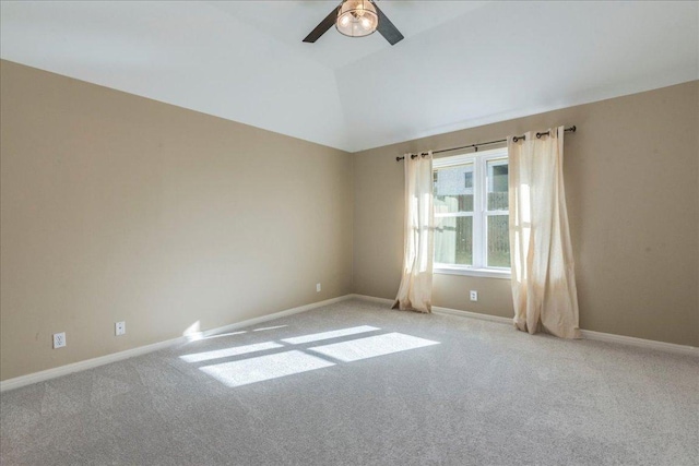 carpeted empty room featuring baseboards, a ceiling fan, and vaulted ceiling