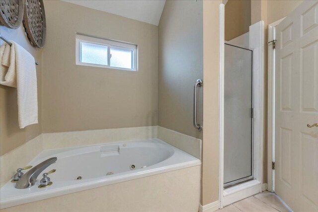 bathroom featuring tile patterned flooring, a tub with jets, and a stall shower