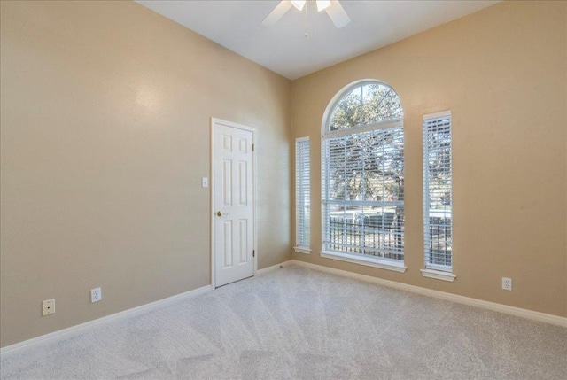 unfurnished room featuring a ceiling fan, baseboards, and light carpet