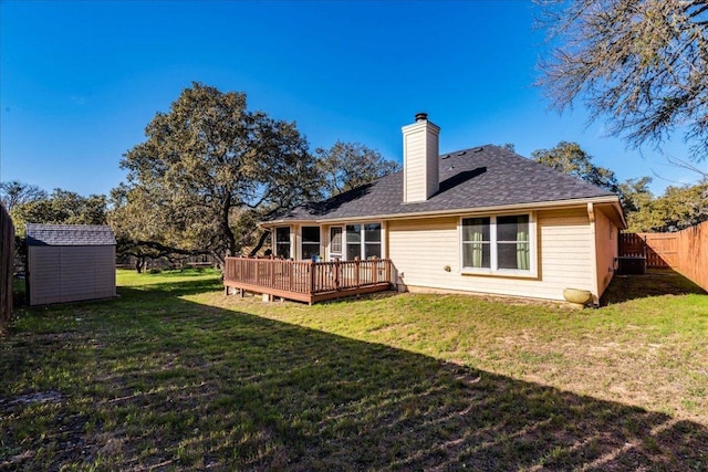 rear view of house featuring an outbuilding, a fenced backyard, a storage unit, a deck, and a lawn