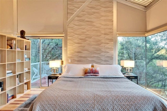 bedroom featuring access to outside, wood finished floors, a towering ceiling, and ornamental molding