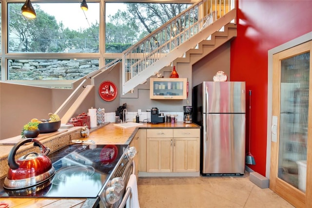 kitchen featuring light tile patterned floors, a sink, appliances with stainless steel finishes, and plenty of natural light