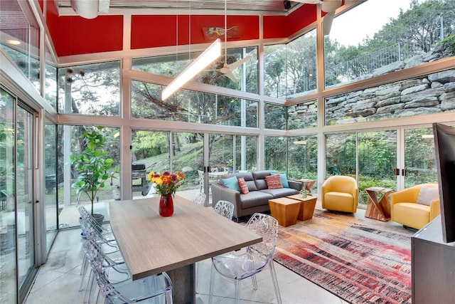 sunroom / solarium featuring a towering ceiling, a healthy amount of sunlight, and floor to ceiling windows