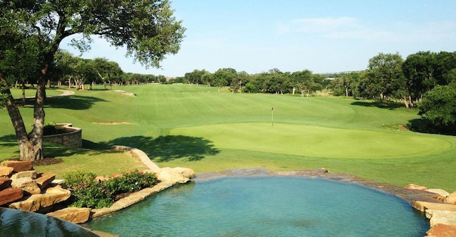 view of community featuring view of golf course and a yard