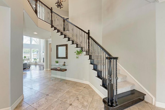 stairs featuring a high ceiling, recessed lighting, baseboards, and a chandelier