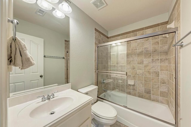 full bath with visible vents, toilet, vanity, and bath / shower combo with glass door