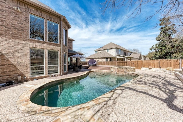 view of swimming pool with a fenced backyard and a pool with connected hot tub