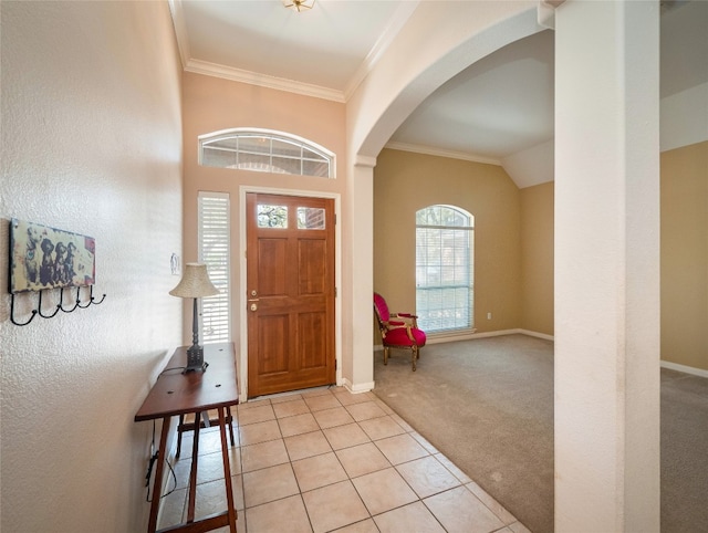 foyer entrance featuring baseboards, light tile patterned flooring, arched walkways, crown molding, and light colored carpet