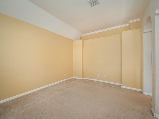 empty room with arched walkways, visible vents, light colored carpet, and baseboards