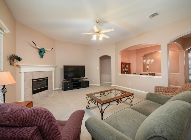 living room with visible vents, carpet floors, baseboards, arched walkways, and ceiling fan with notable chandelier