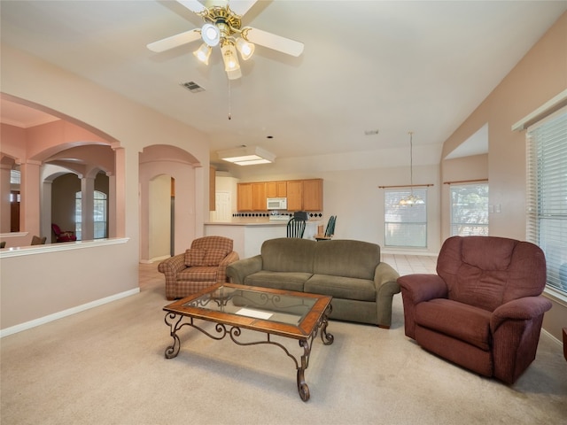 living area featuring visible vents, carpet floors, arched walkways, baseboards, and ceiling fan