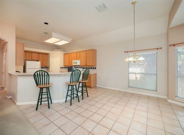 kitchen with visible vents, a breakfast bar, white appliances, a peninsula, and light countertops