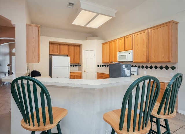 kitchen featuring visible vents, light tile patterned floors, decorative backsplash, a peninsula, and white appliances