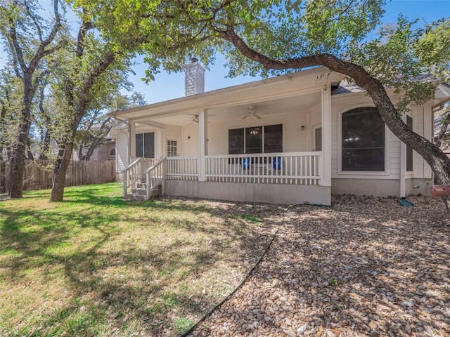 view of front of home with a chimney, ceiling fan, a front lawn, and fence