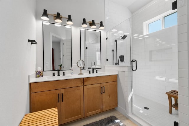 full bathroom with a sink, double vanity, wood finished floors, and a shower stall