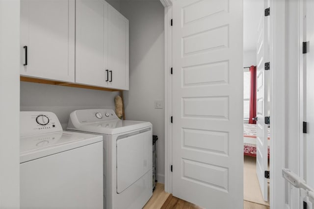 clothes washing area featuring cabinet space, light wood-style flooring, and washer and clothes dryer