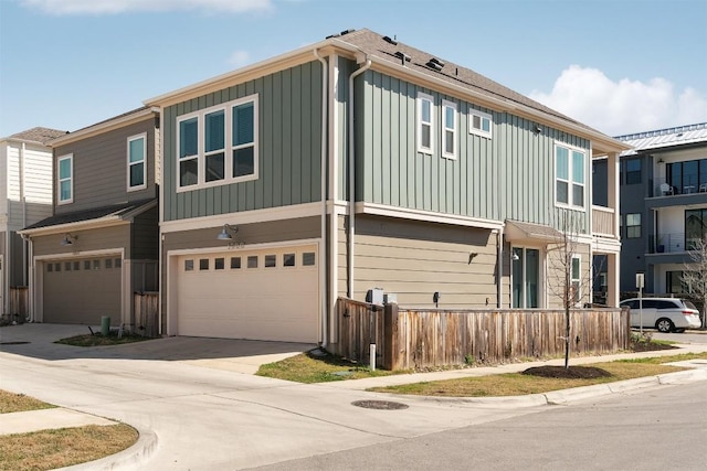 multi unit property featuring board and batten siding, driveway, a garage, and fence