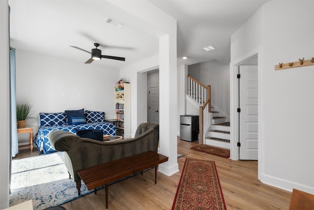 living area with wood finished floors, stairway, baseboards, visible vents, and a ceiling fan