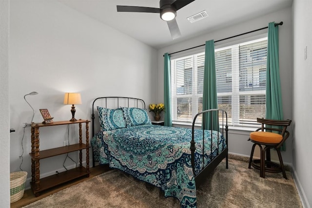 carpeted bedroom featuring baseboards, visible vents, a ceiling fan, and multiple windows