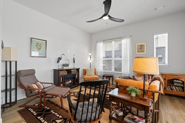 living area featuring a ceiling fan, visible vents, and a healthy amount of sunlight