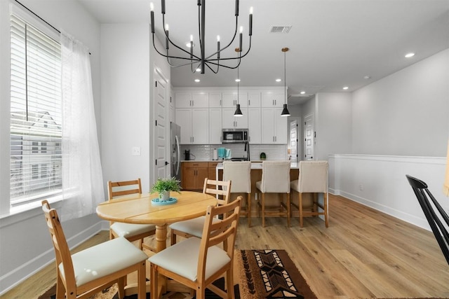 dining area with visible vents, baseboards, light wood-style floors, and a notable chandelier