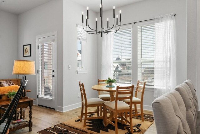 dining room with baseboards, an inviting chandelier, and light wood finished floors