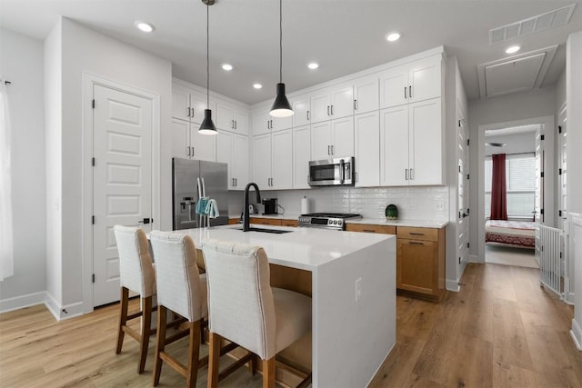 kitchen with visible vents, light wood-style flooring, a sink, a kitchen breakfast bar, and stainless steel appliances