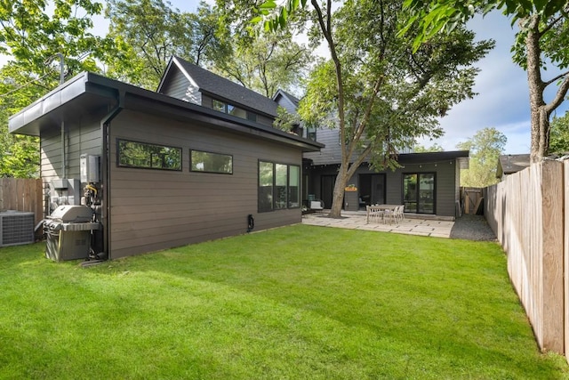 back of house with central AC unit, a patio, a lawn, and a fenced backyard