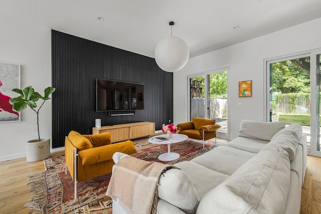 living area featuring baseboards, light wood-style flooring, and an accent wall