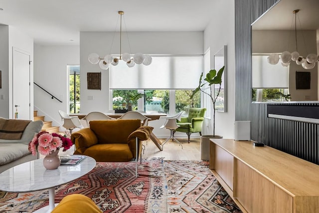 living room featuring a chandelier, stairs, a wealth of natural light, and wood finished floors