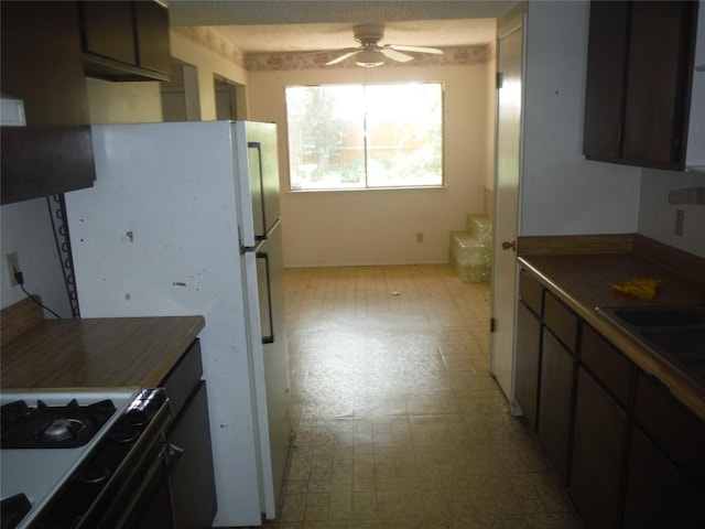 7729 Croftwood Dr, Austin, TX 78749 - kitchen featuring gas range oven, light flooring, a ceiling fan, dark countertops, and a sink
