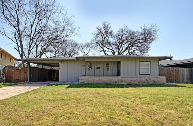 ranch-style home with a carport, board and batten siding, a front lawn, and fence