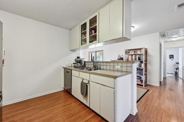 5303 Kings Hwy, Austin, TX 78745 - kitchen featuring stainless steel dishwasher, light wood-type flooring, a sink, glass insert cabinets, and baseboards
