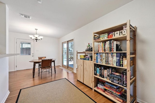 dining room featuring baseboards, wood finished floors, visible vents, and a chandelier