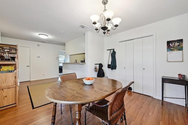 dining room featuring light wood-type flooring, visible vents, and a chandelier