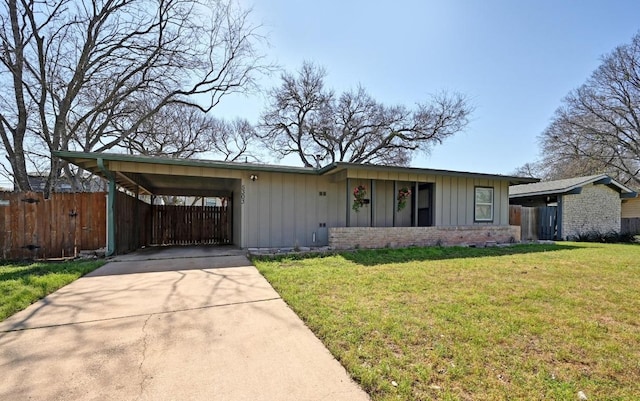 view of front of home with an attached carport, board and batten siding, a front lawn, fence, and concrete driveway