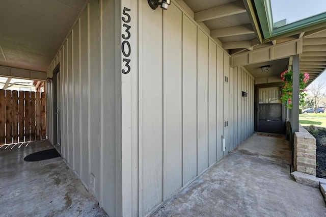 view of exterior entry featuring fence and board and batten siding